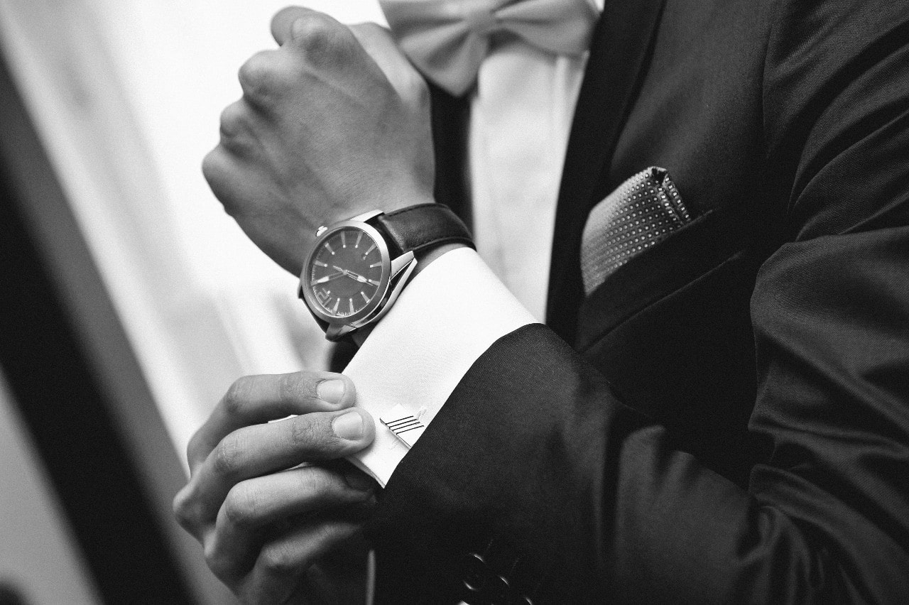 close-up of man&rsquo;s wrist wearing a luxury watch and suit