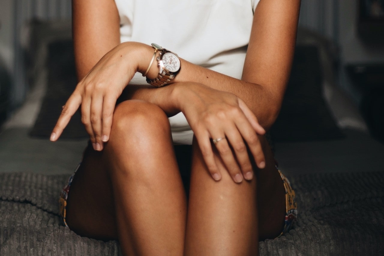 lady&rsquo;s torso with her legs and arms crossed, wearing a luxury watch