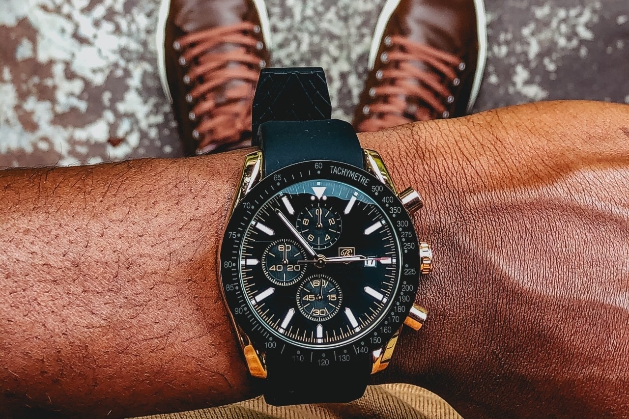 a man&rsquo;s wrist wearing a black Breitling timepiece