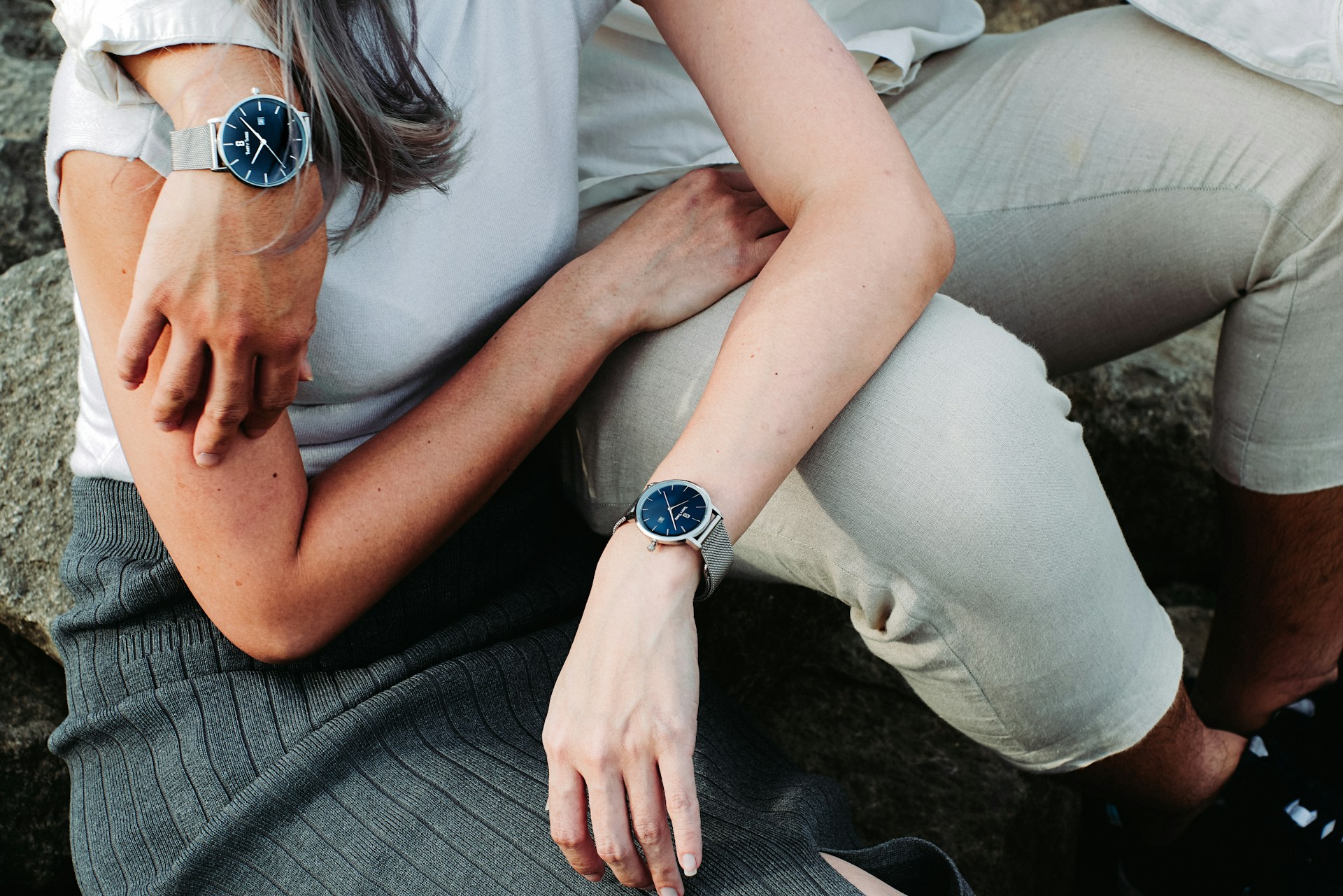 a couple wearing luxury timepieces sitting down embracing