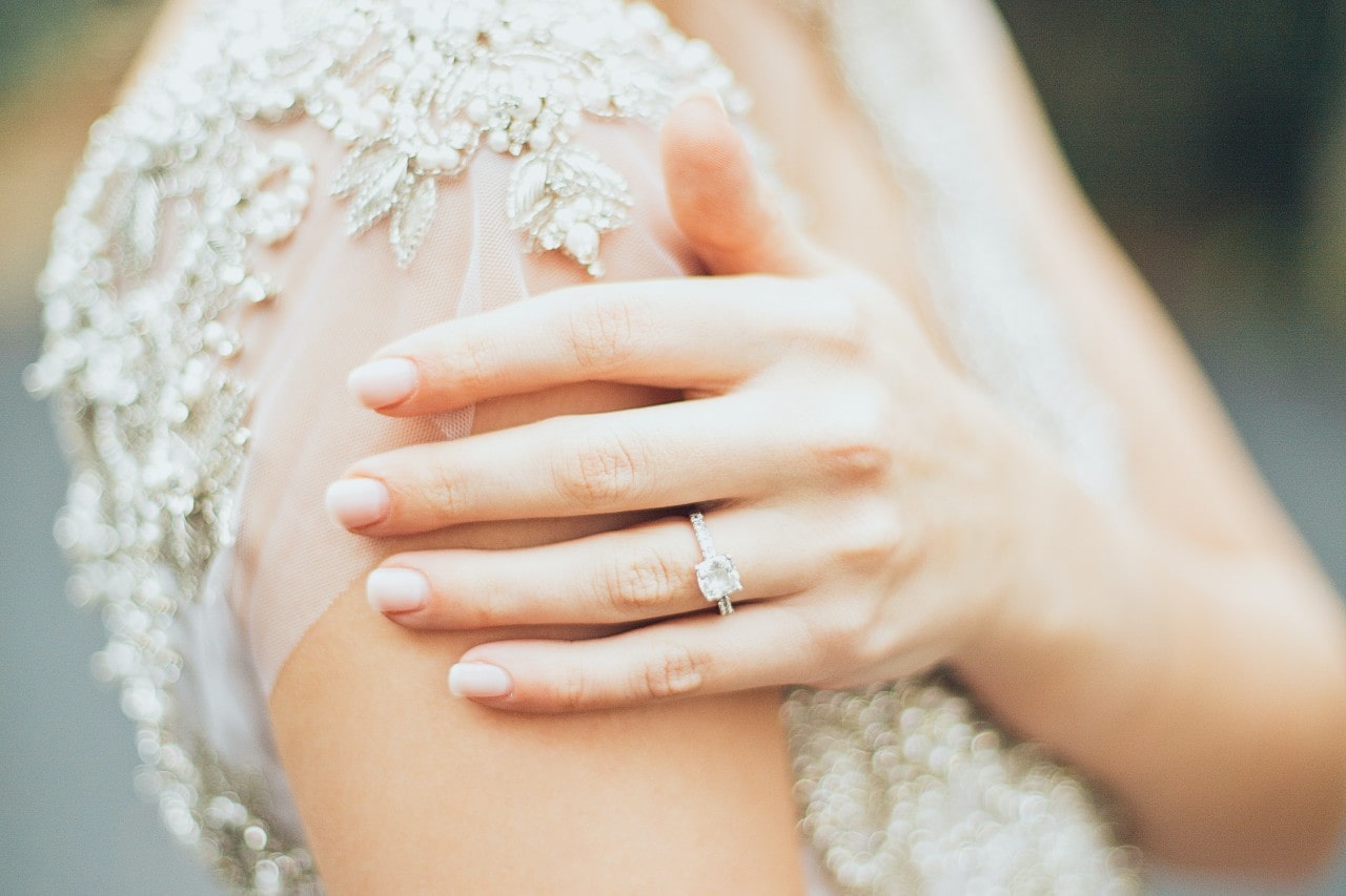side stone engagement ring on a bride&rsquo;s finger.