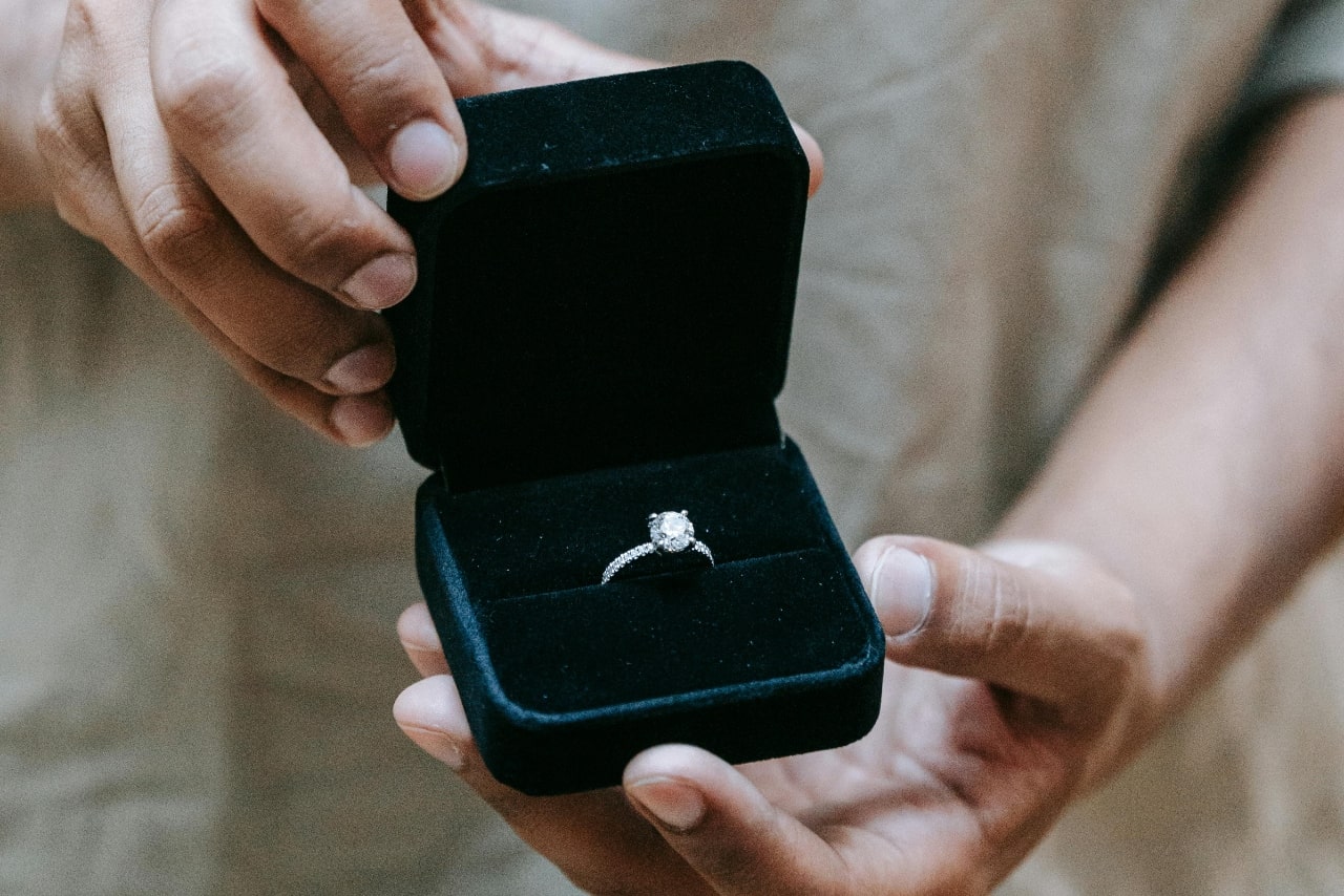 A white gold diamond side stone engagement ring in a green velvet box