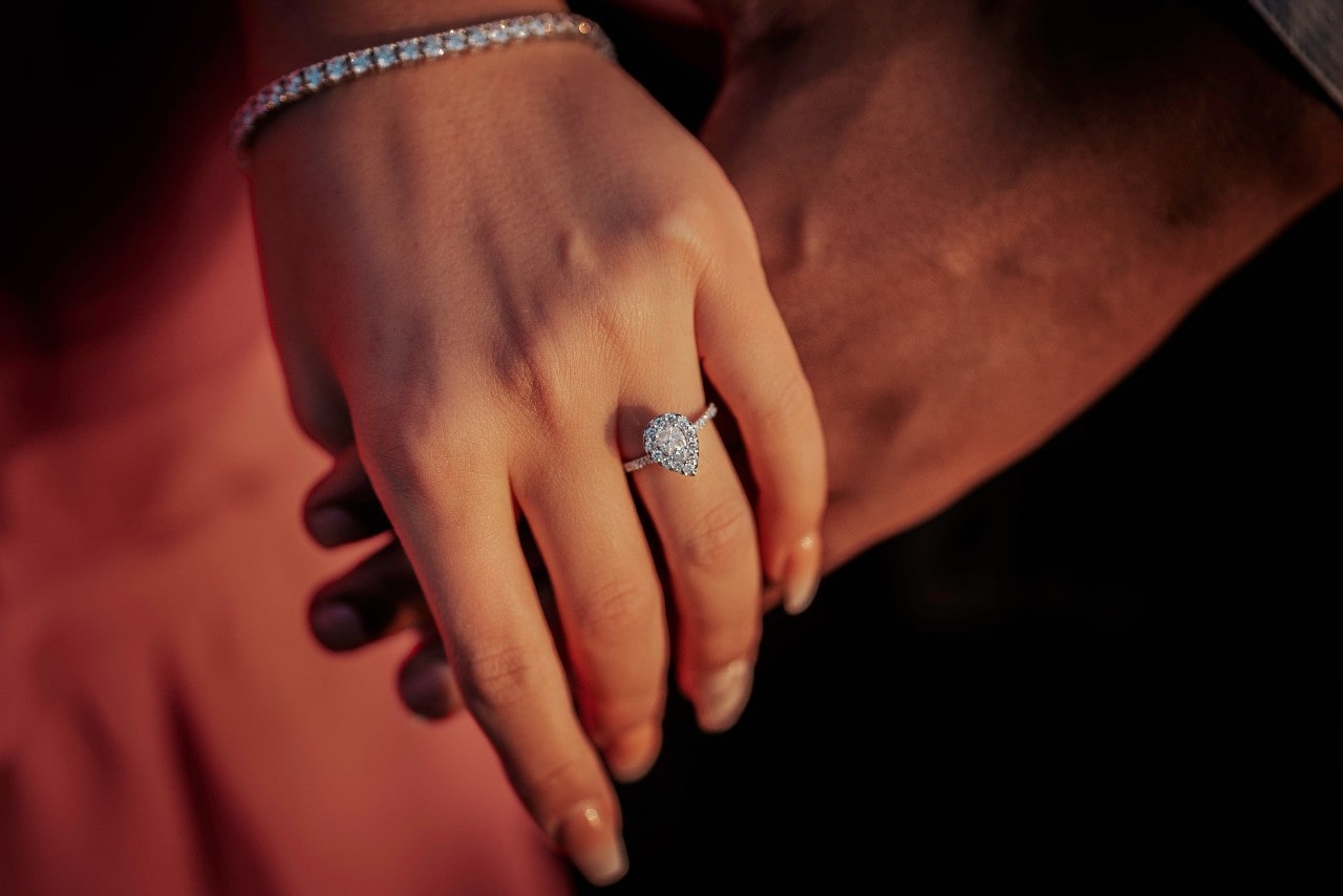 A white gold diamond pear shaped engagement ring on a woman’s hand