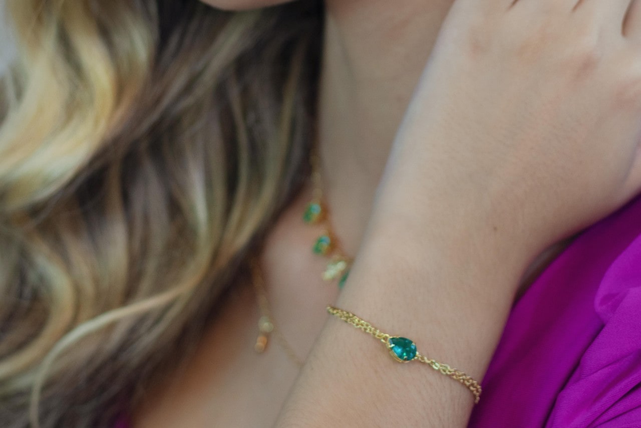 A close up image of a woman’s wrist adorned with a green gemstone bracelet.