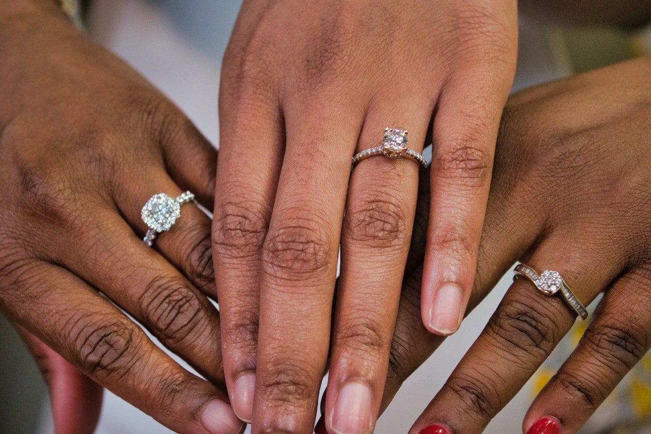three hands wearing engagement rings of varying styles three hands wearing engagement rings of varying styles